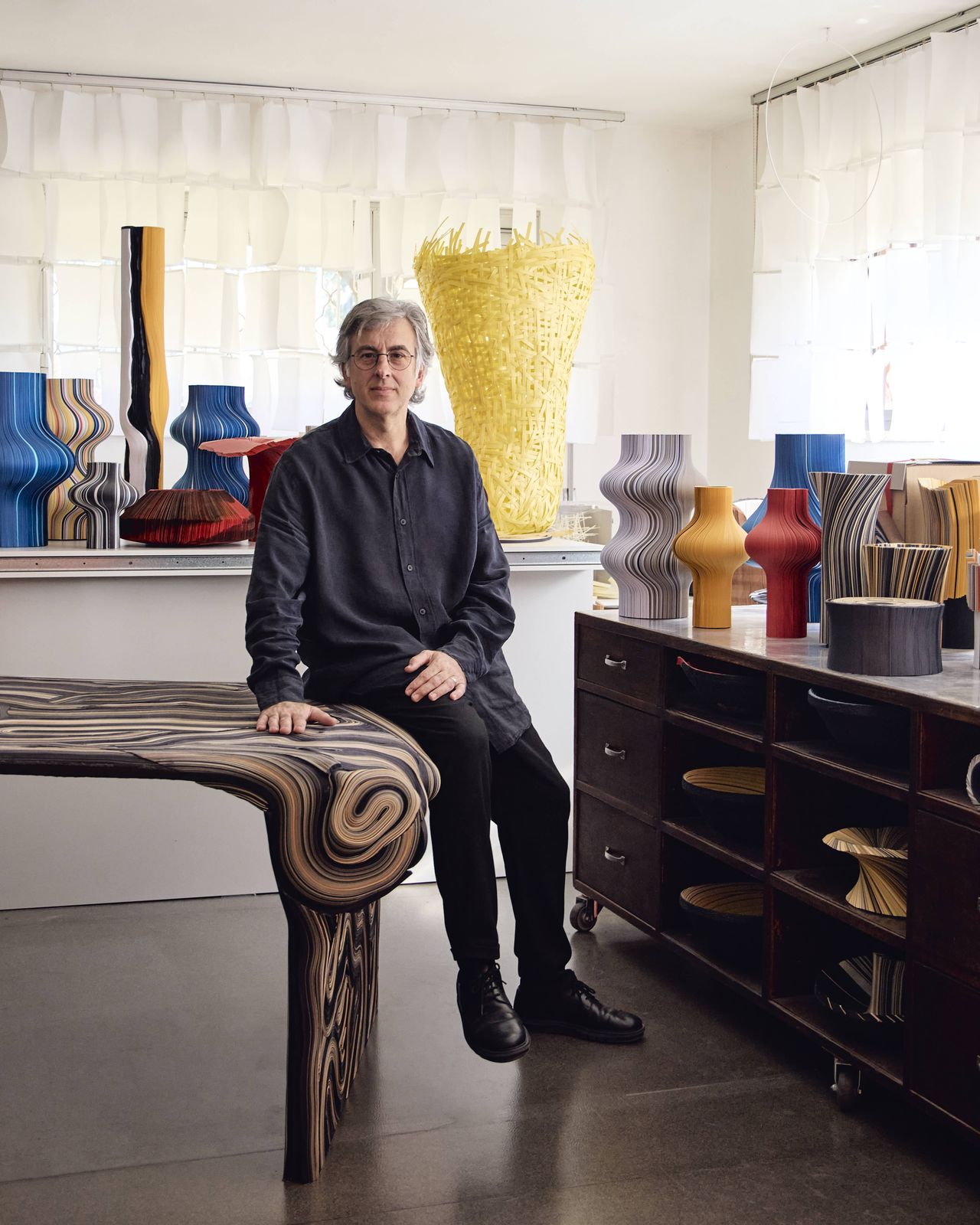 Portrait of Daniele Papuli next to his paper furniture and objects