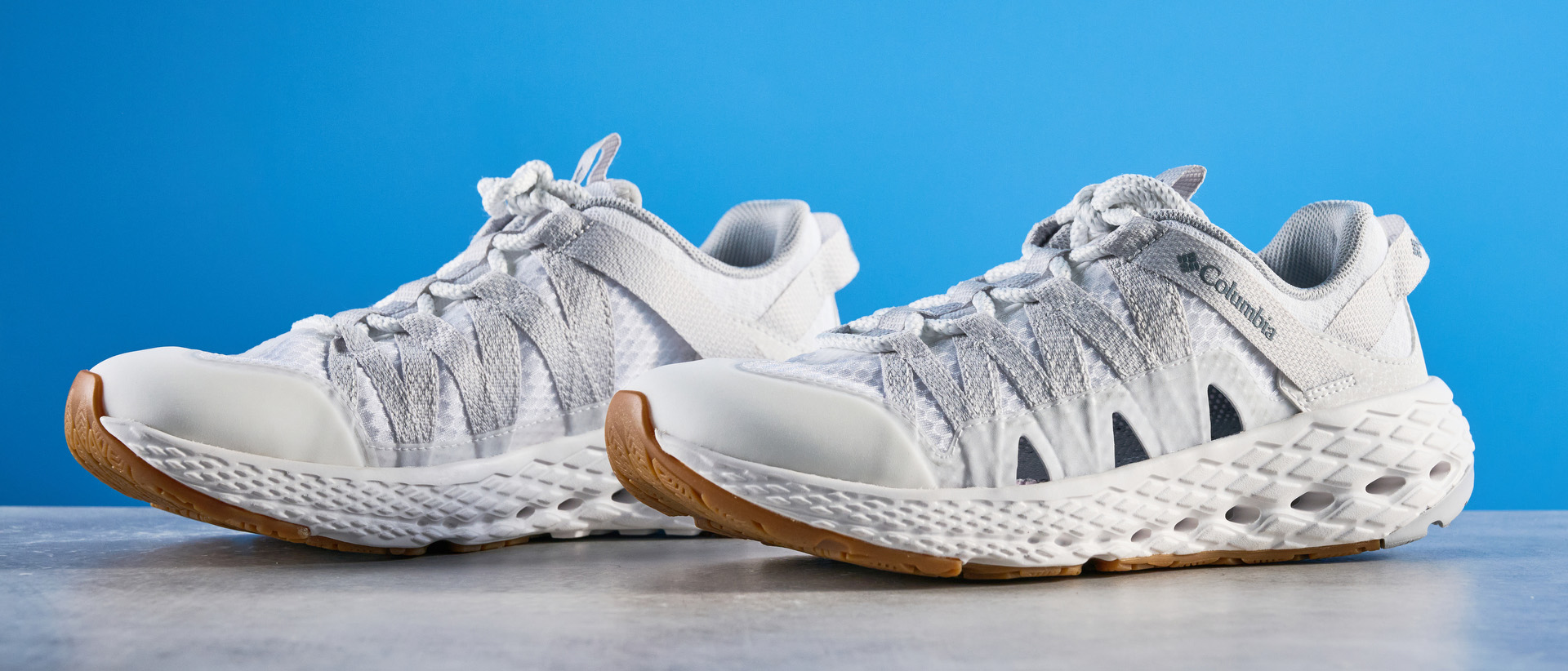 Columbia Drainmaker shoes in white photographed in front of a blue background.