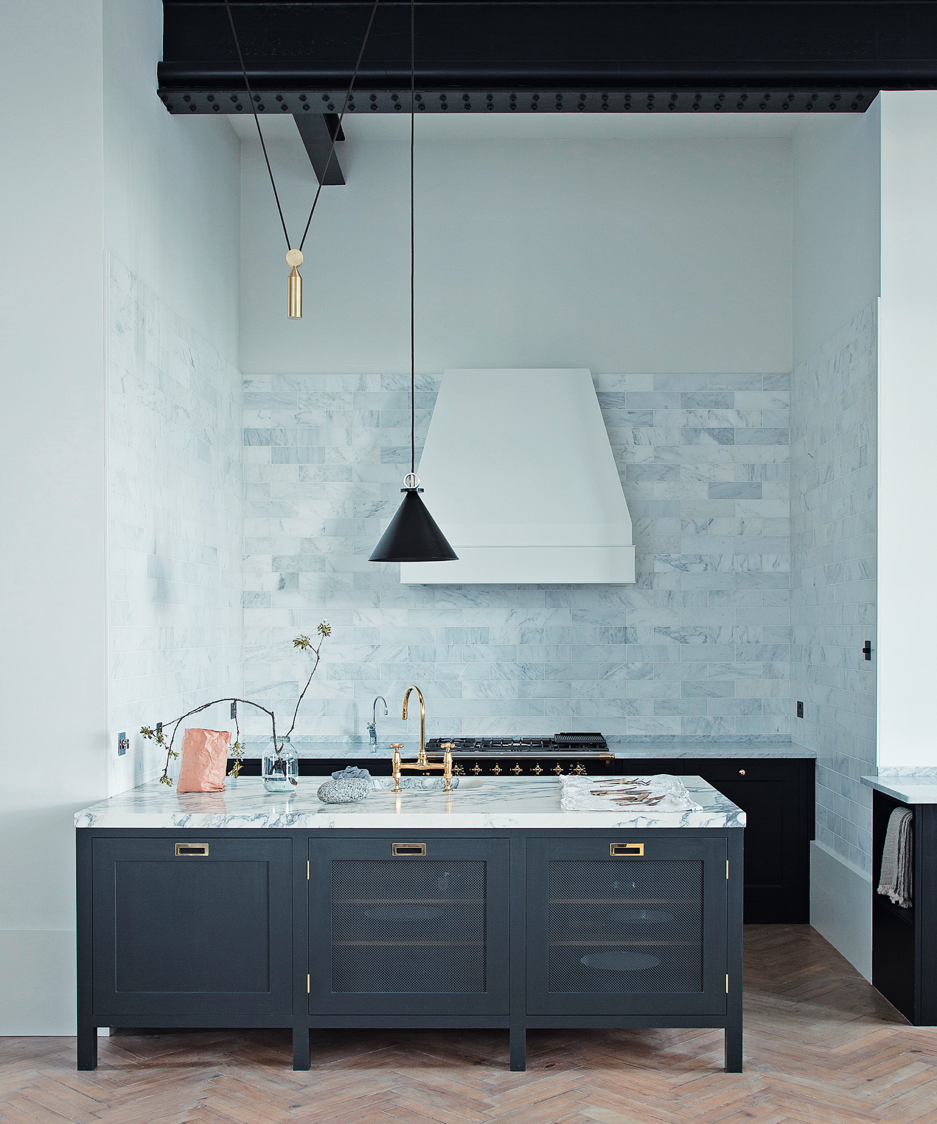 An example of small kitchen layout ideas showing a dark green peninsula with a marble worktop, light blue wall tiles and a white extractor fan