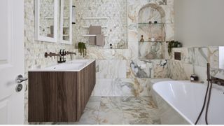 Elegant marble titled bathroom with a wooden vanity sink basin curved bath and archway built-in wall shelves