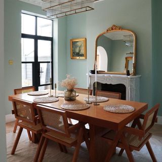 Dining room area painted green with wooden table and chairs in the centre