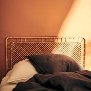 beige bedroom with dark bedding and a rattan headboard