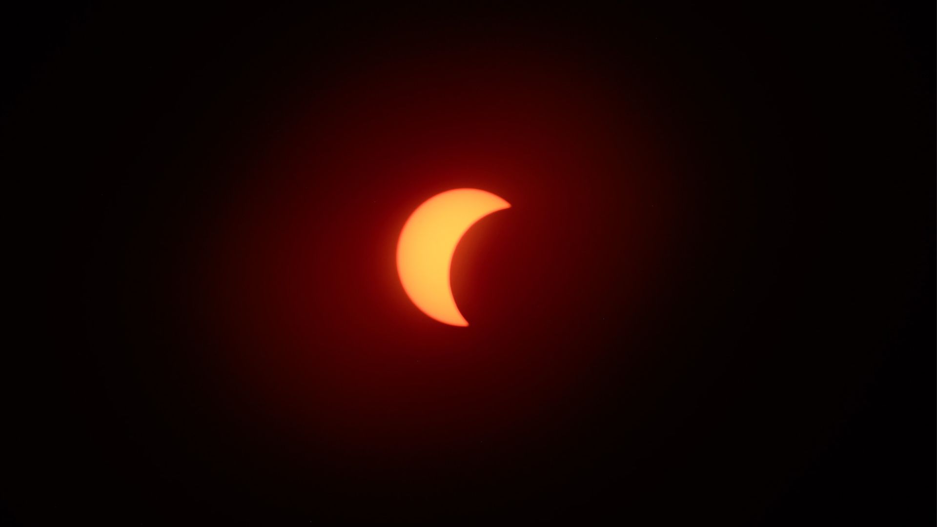 The eclipsed sun is photographed in a black sky during the partial phase of a total solar eclipse.