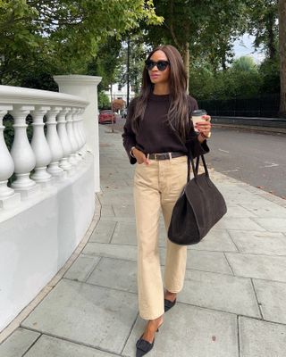 Woman wears brown jumper, beige jeans and brown bag