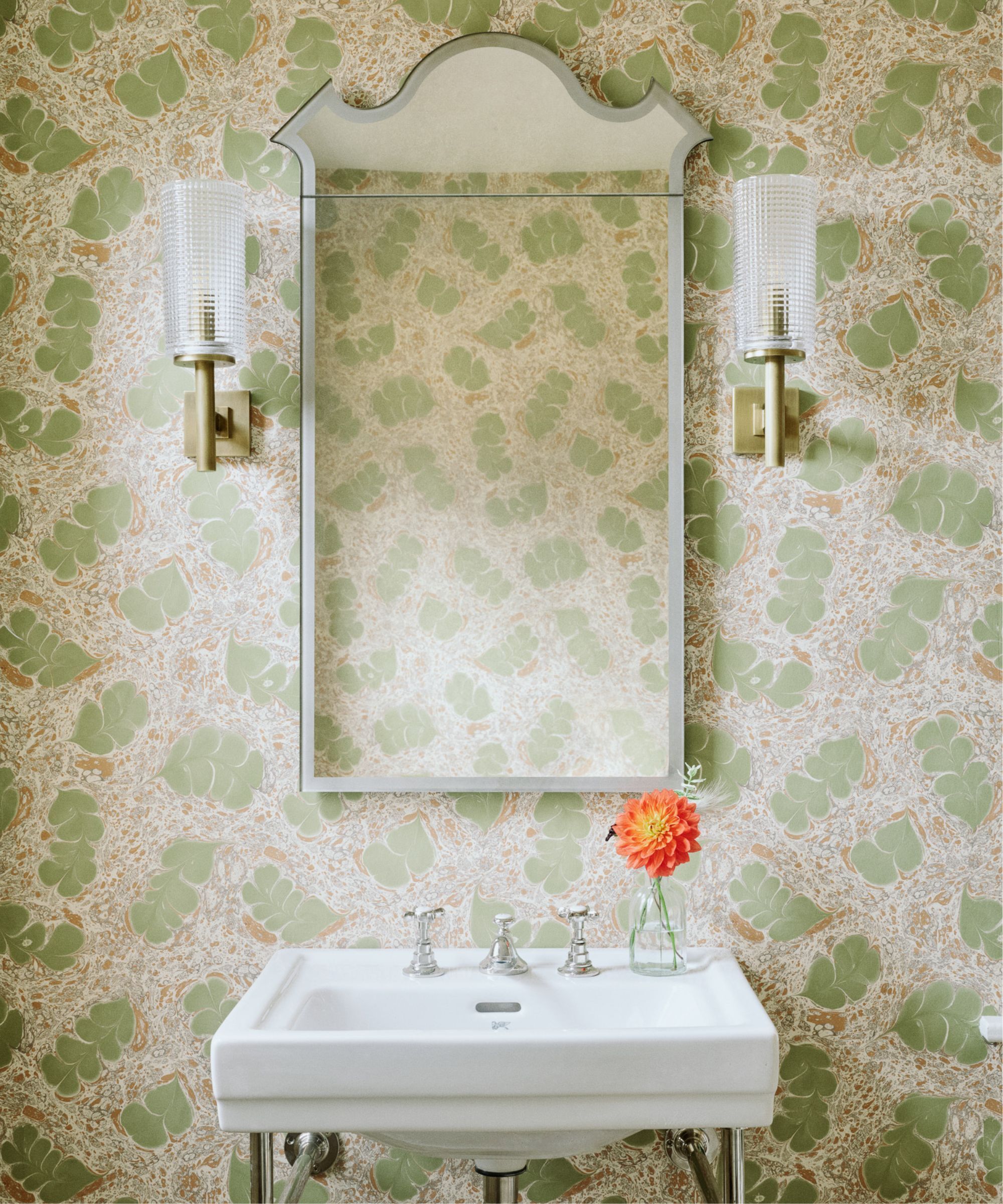 Bathroom sink with over sink mirror and green patterned wallpaper