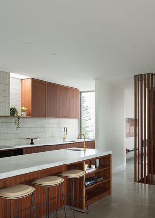 a sleek kitchen with wood elements as well as white tiling and white countertops