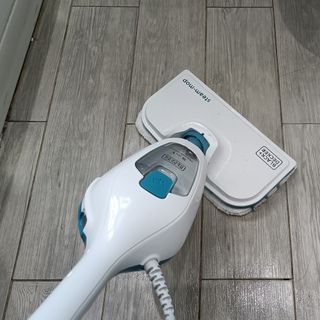 Black & Decker 10-in-1 Steam Mop cleaning a wood effect tiled floor as seen from above.