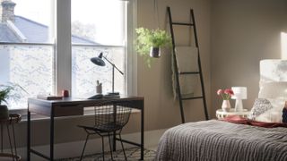 bedroom with ladder storage and desk below window with lower half covered in window film