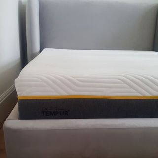 The Tempur Sensation Elite mattress on a grey upholstered bed frame