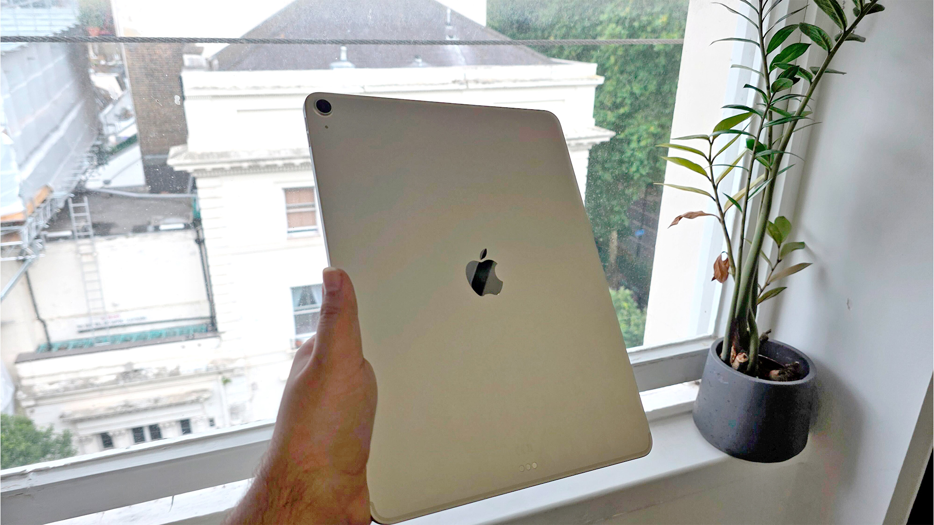 Apple iPad Air 13-inch (2025) tablet held in hand in front of window showing back of tablet