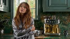 Kelly Wearstler in a green kitchen beside a Breville Mixed Metals silver and brass coffee maker