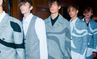 a line of male models wearing grey blazers