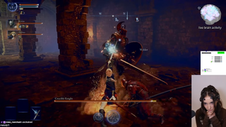 The streamer PerriKaryal is seen concentrating via a picture-in-picture stream. She's playing Elden Ring: Nightreign via a hands-free EEG control scheme. Her hands are seen, clasped under her chin, in a contemplative gesture as she stares intently at the game screen.