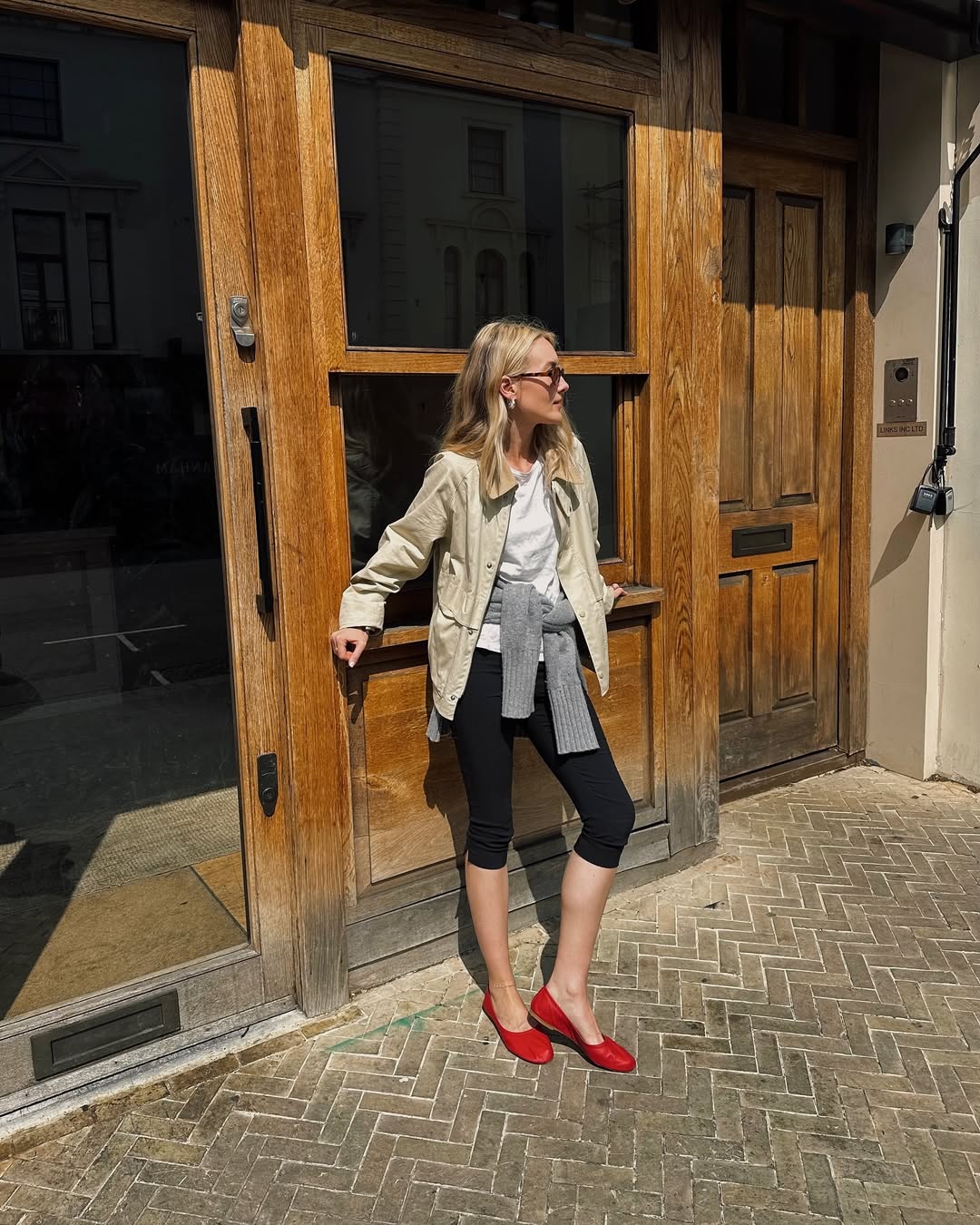 @chloekathbutler wears a barn jacket, white t-shirt, black capri leggings and red mesh flats