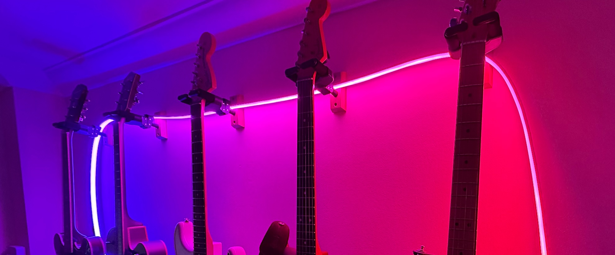 Hue Omniglow Lightstrip draped over some guitar hangers in a dark room