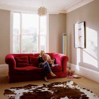 living room with red sofa woman and floor rug
