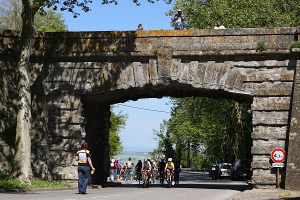 The bunch passes under the bridge at Fanjeaux.