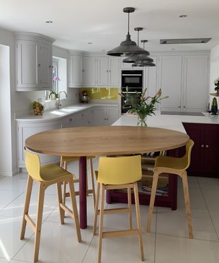 tall round kitchen table with yellow upholstered stools at end of kitchen island
