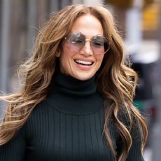 Jennifer Lopez looking away from the camera and smiling wearing large sunglasses