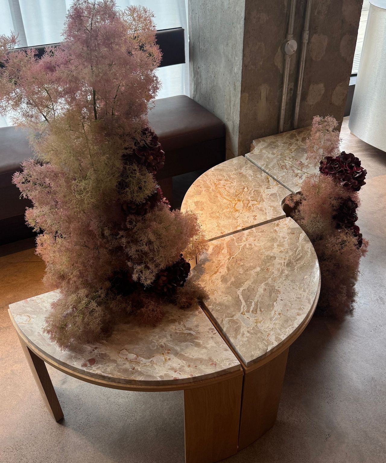close up of marble-topped timber semi-circle coffee tables arranged in a squiggly line with flowers
