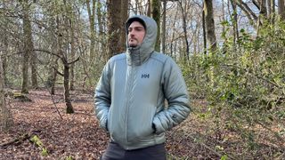 Hiker wearing Helly Hansen Odin Everdown hooded jacket in the woods