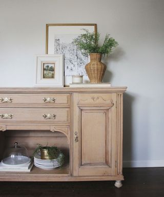 Refinished wooden buffet in hallway with a vase of flowers and frame on the top