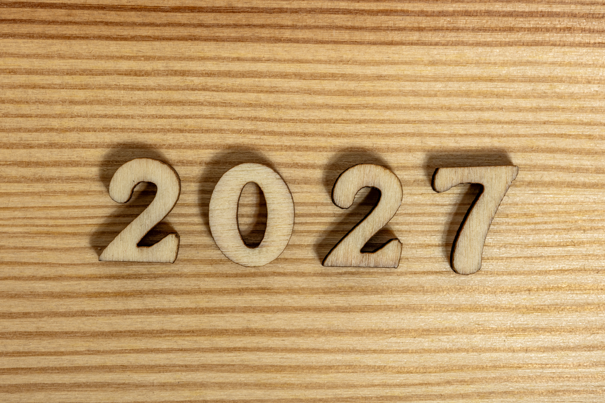 Closeup wooden cutout numbers forming 2027 year symbol on natural surface background