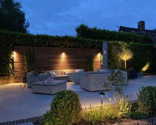 entertaining space in night garden with lighting, furniture and fire pit