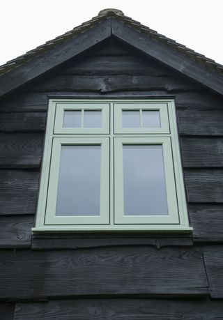 green traditional style window on a black timber clad building