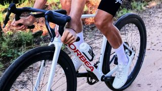 A white and red Orbea Terra gravel bike being ridden