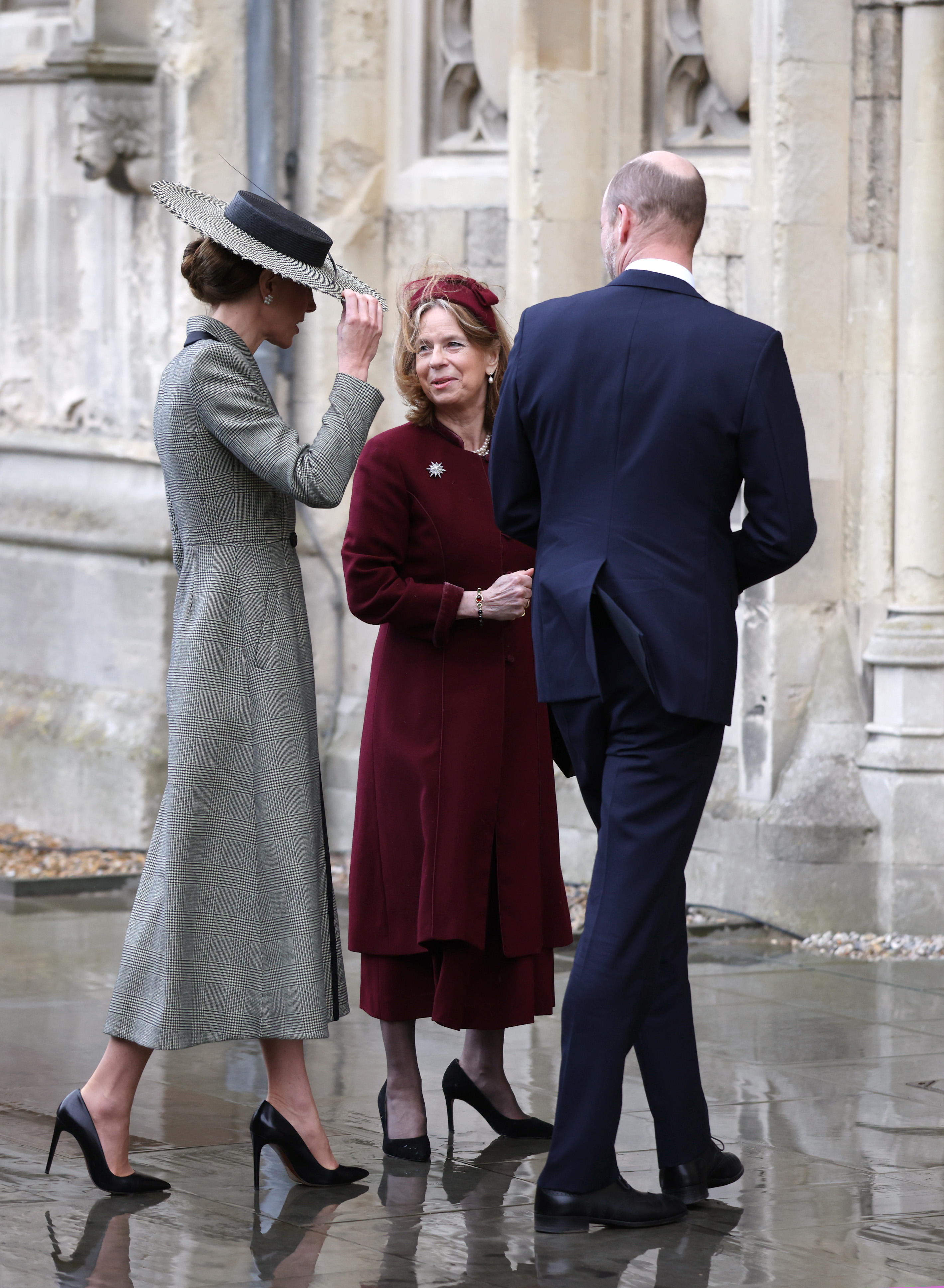 Princess Kate wearing a gray coat walking with Prince William and a woman into church