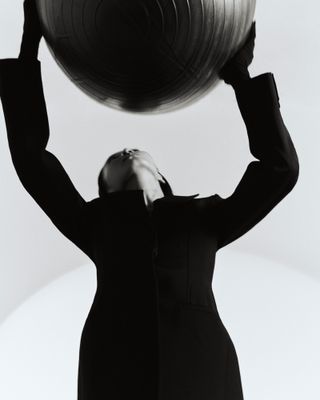 Woman in black outfit holding up ball