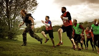 People taking a British Military Fitness bootcamp class run up a hill following an instructor