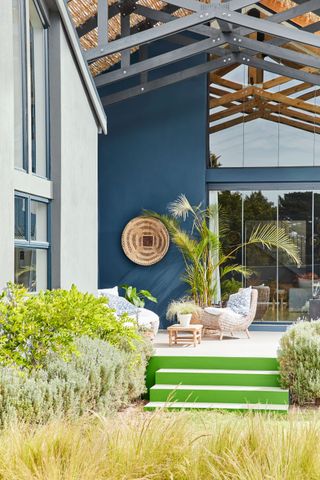 An example of large backyard ideas showing a colorful terrace leading down to a garden with wild grasses and shrubbery