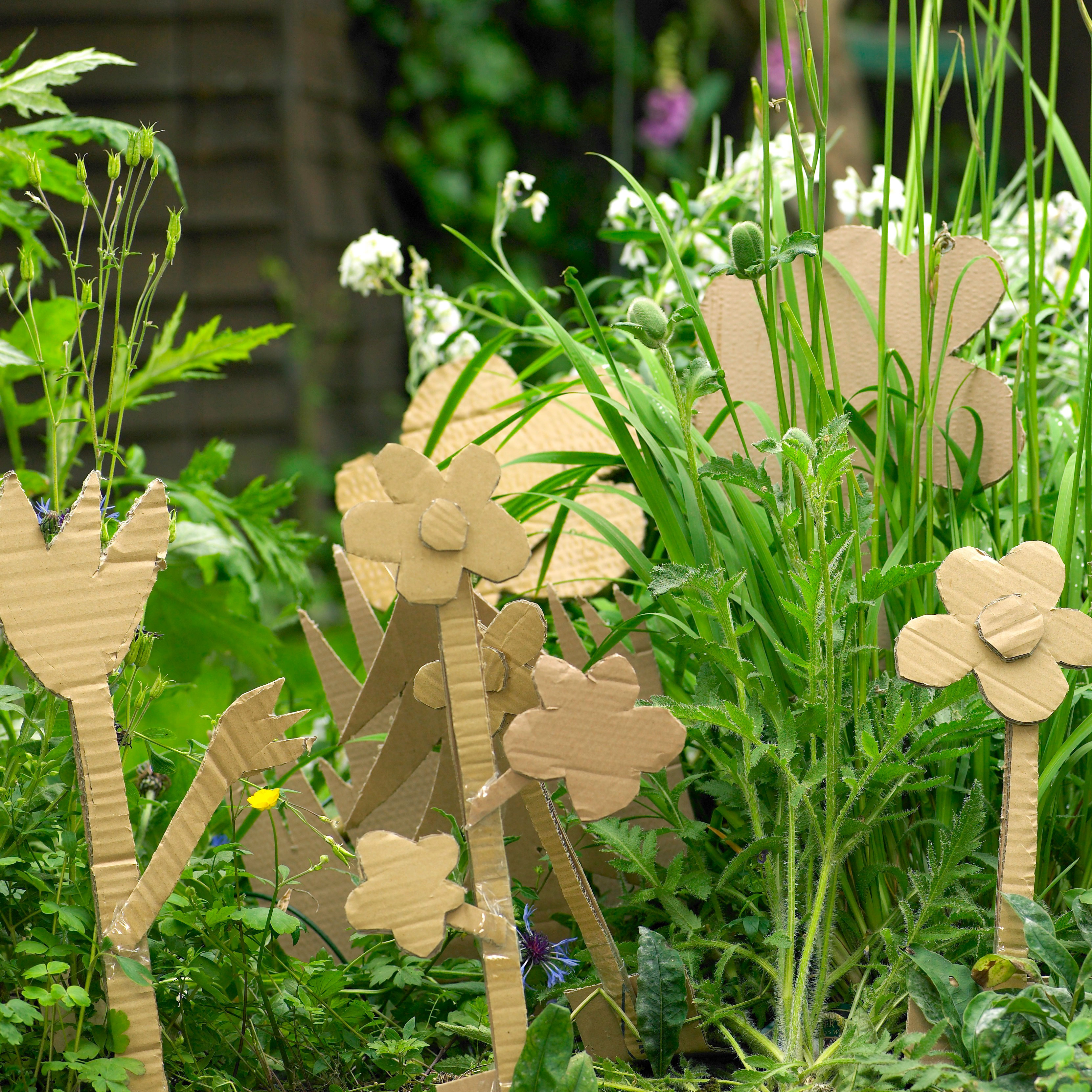  brown cardboard flowers in garden with grass