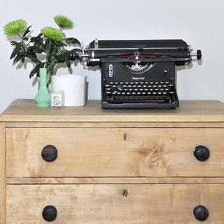 typewriter on wooden drawers and white wall