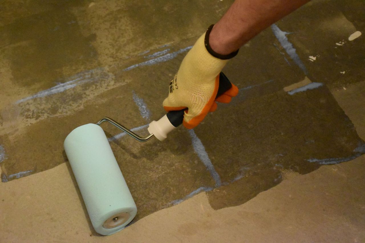Rollering on a primer to the floor before sticking down herringbone wooden flooring