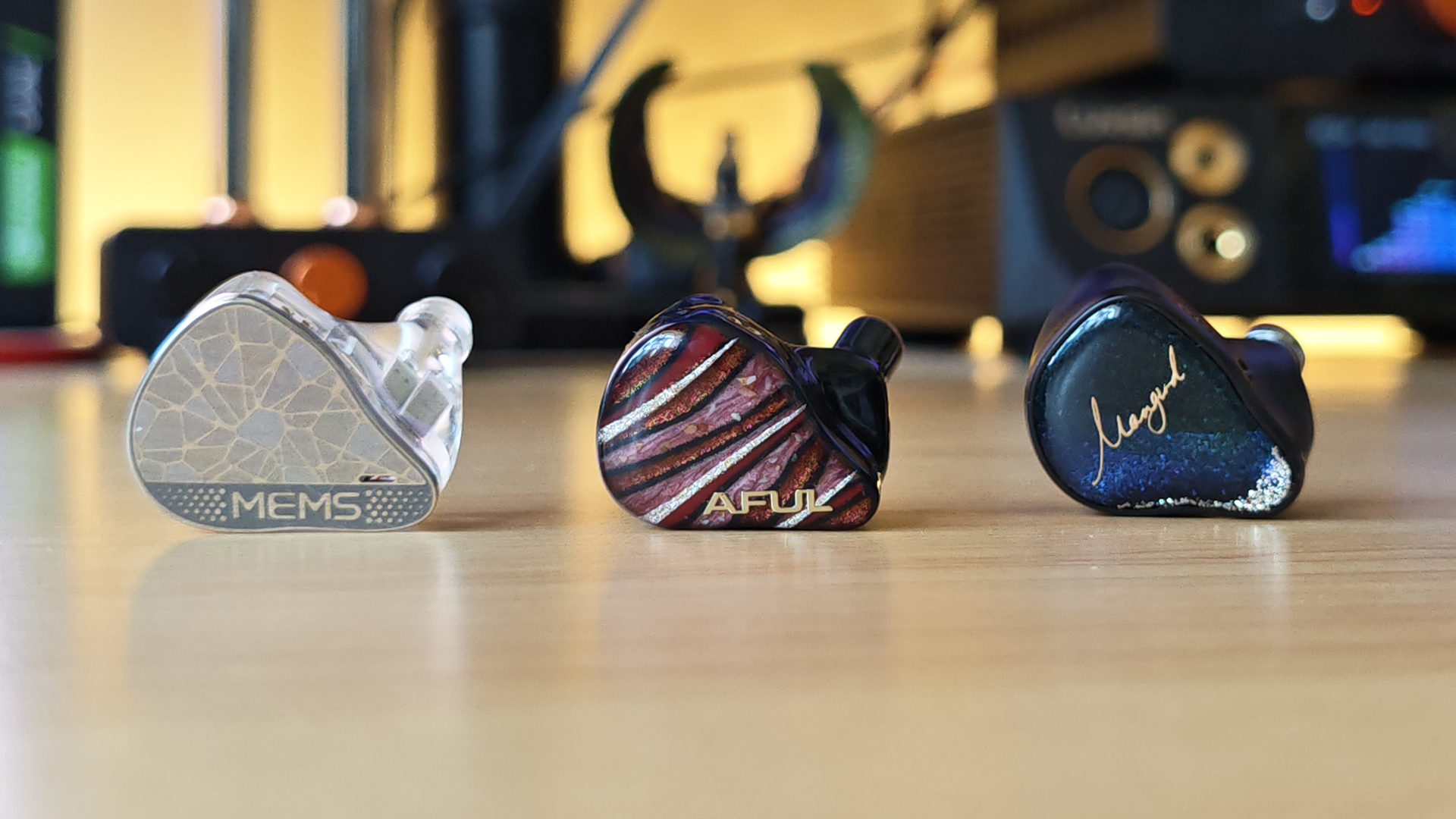 Three IEMs on a wooden desktop.