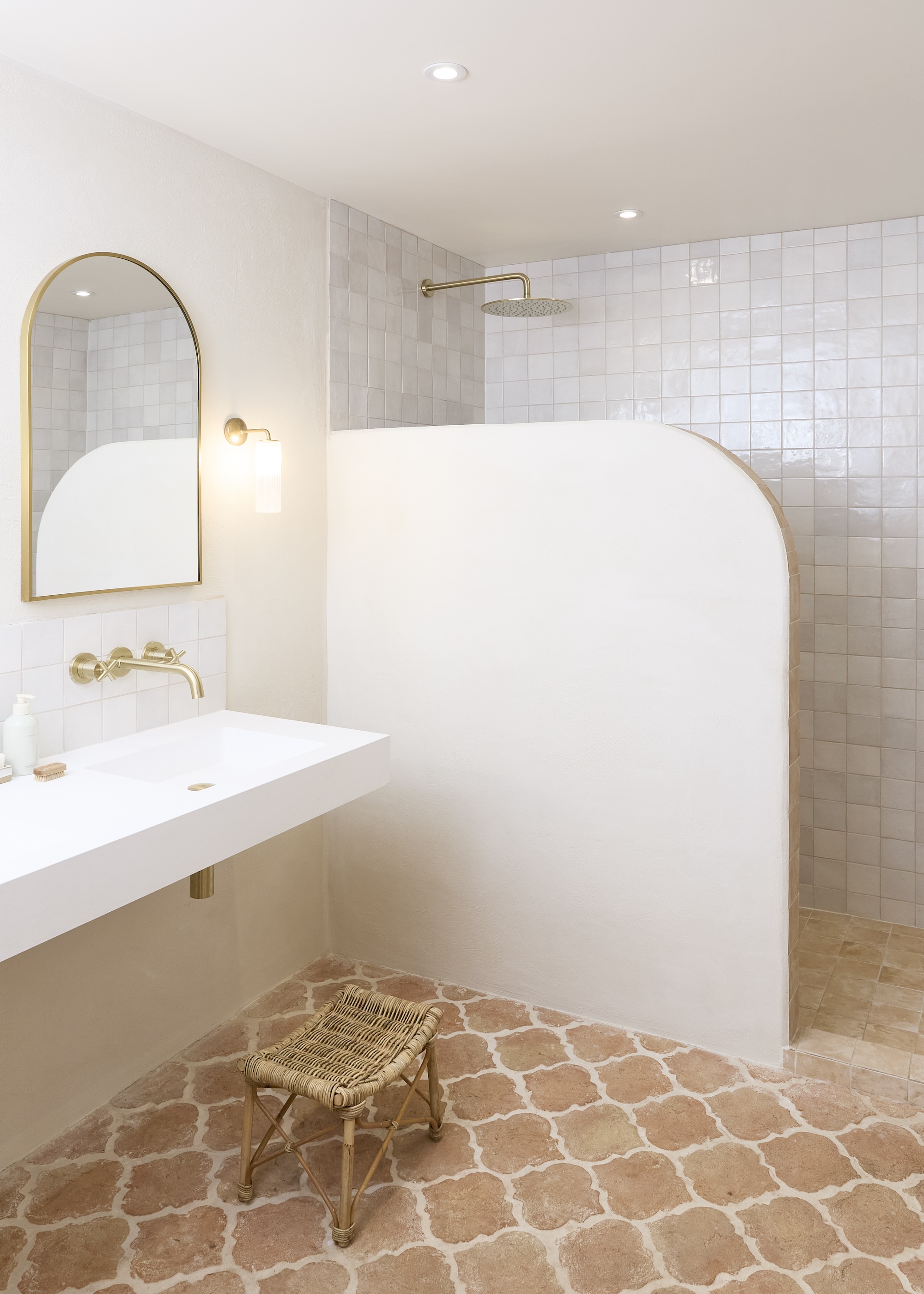 a neutral toned ensuite bathroom with a walk in shower and curved built in shower screen