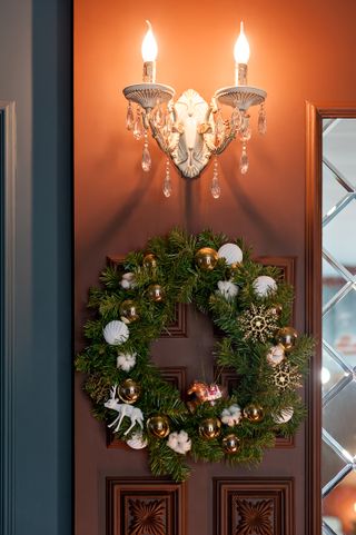 A traditional bright Christmas wreath hanging over the fireplace