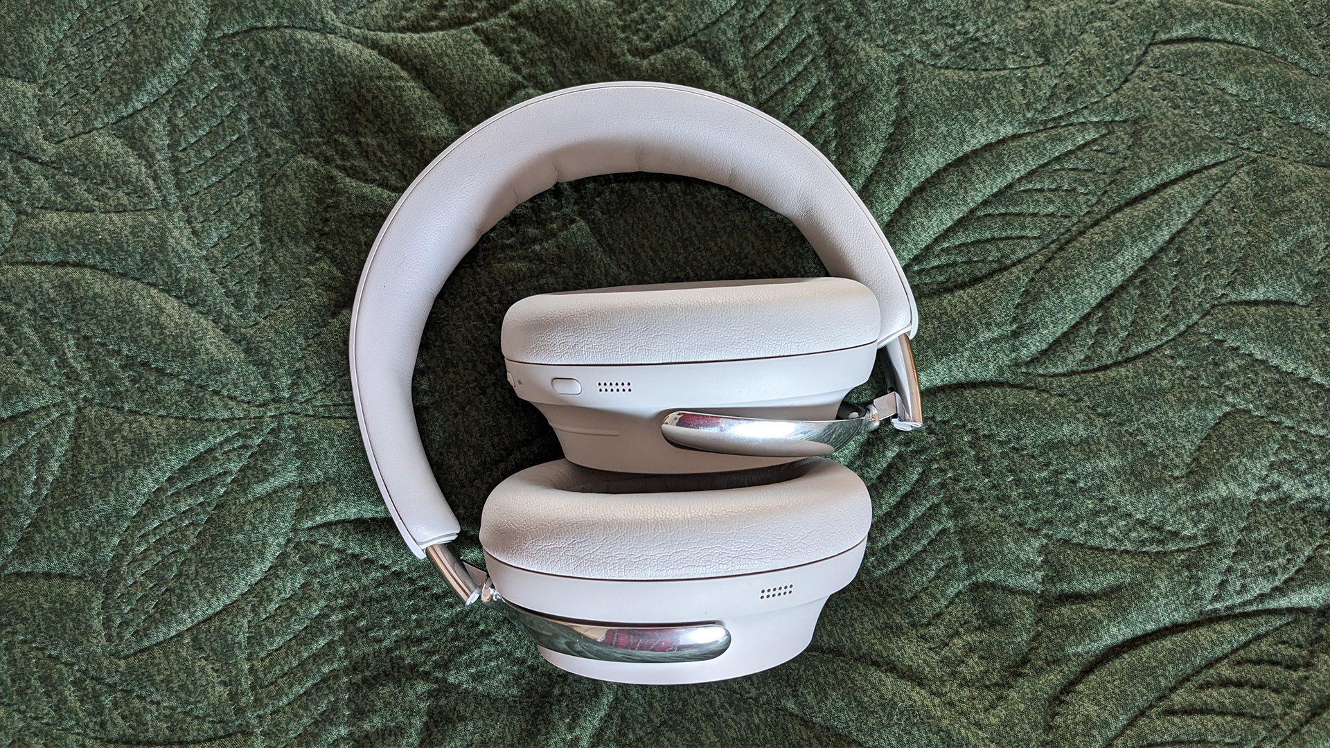 Bose QuietComfort Ultra Headphones (2nd Gen) noise-cancelling headphones in white on green fabric, folded down