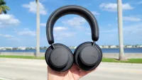 The Urbannista Los Angeles headphones being held aloft against a backdrop of a coastal street and the Intracoastal Waterway 