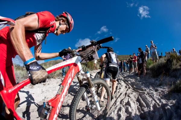 Riders pushes their bikes up sandy inclines