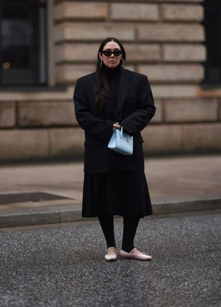 Jennifer Casimiro wearing black sunglasses, silver diamond earrings, Vintage black oversized blazer, COS black high neck cotton pleated midi dress, Lululemon black leggings pants, Strathberry light blue leather bag and Miu Miu light pink satin logo ballerina