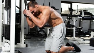 Man performing cable crunch in gym