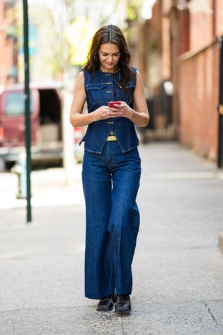 Katie Holmes wearing the denim-on-denim trend in a jean vest and jean trousers in New York City.