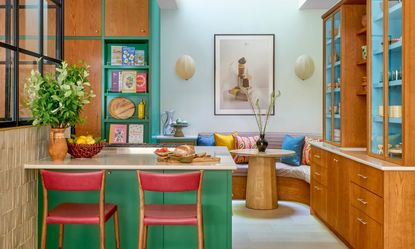 Bespoke kitchen with rich wood cabinets, blue shelving and green island with red bar stools