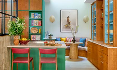 Bespoke kitchen with rich wood cabinets, blue shelving and green island with red bar stools