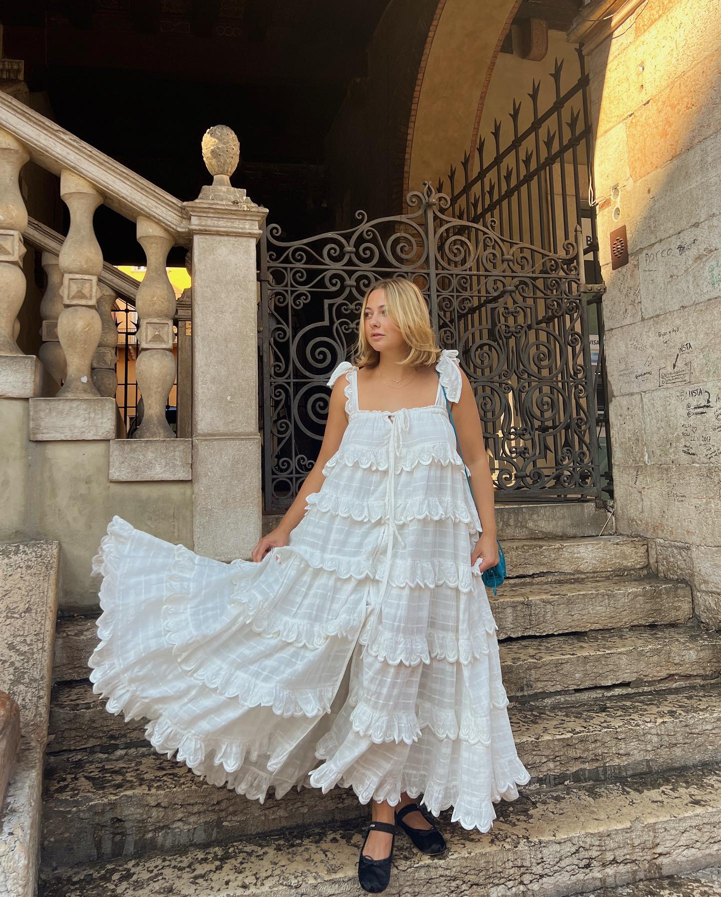 Woman on stairs wears ruffled white dress with bows
