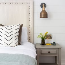 A bed with a grey bedside table next to it